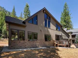Nestled amidst towering pine trees and a mountainous backdrop, this stunning home offers a unique architectural design with expansive windows that flood the interior with natural light.