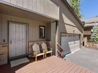 Welcome guests to this charming mountain home with a cozy front porch featuring two Adirondack chairs.