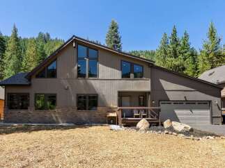 Nestled amidst a serene forest, this modern mountain home offers a striking architectural design with its unique A-frame windows and warm, earthy tones.