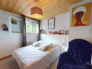 This cozy bedroom features a comfortable queen-sized bed with a textured white duvet, perfect for a restful night's sleep.