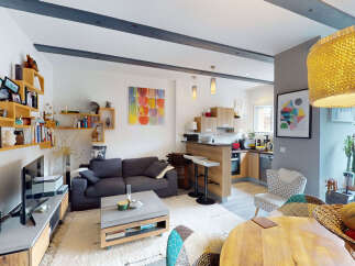 Discover this charming living space featuring a cozy dark gray sofa, a modern coffee table, and an adjacent kitchen with a breakfast bar.