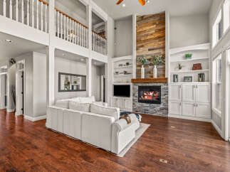 Experience luxury living in this stunning home featuring a grand living room with a soaring ceiling and a magnificent stone fireplace as the focal point.