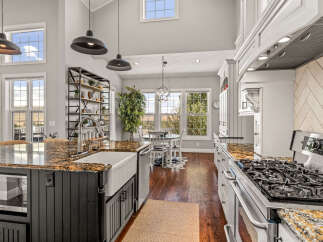 Experience luxury and comfort in this stunning kitchen, featuring a large granite island with a farmhouse sink and a professional-grade gas range.