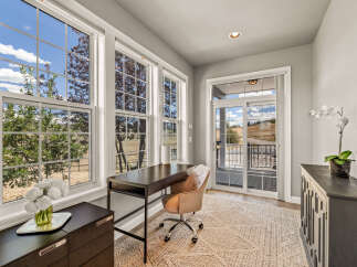 This home office boasts abundant natural light streaming through large, multi-paned windows, offering picturesque views of the surrounding landscape.