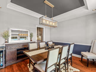 This elegant dining room features a dark wood dining table with upholstered chairs, set against a backdrop of light gray walls and a contrasting navy blue wainscoting.