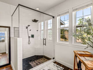 Experience luxury in this modern bathroom featuring a spacious glass-enclosed shower with a sleek black rain showerhead and handheld wand.