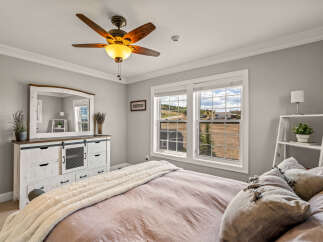 Experience serene country living in this charming bedroom, featuring a rustic distressed dresser with a large mirror and a plush, cozy bed.