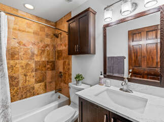 This bathroom features a stunning travertine tile shower surround, complemented by a dark wood vanity and a matching medicine cabinet.
