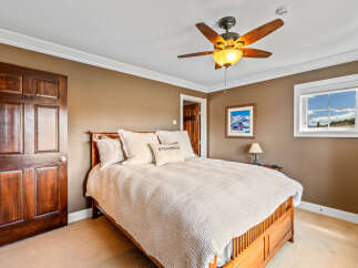 Experience comfort and style in this inviting bedroom, featuring a plush bed adorned with decorative pillows and a cozy knit throw.