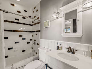 This modern bathroom features a sleek white subway tile shower with striking dark accent tiles, creating a sophisticated look.