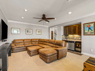 This spacious living area features a large, comfortable sectional sofa perfect for gatherings, complemented by a built-in wet bar with ample cabinet space and a mini-fridge.