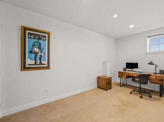 This spacious room features a dedicated workspace with a rustic wooden desk, a comfortable office chair, and a computer setup.
