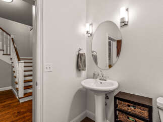 Step into this charming powder room featuring a sleek pedestal sink and a stylish oval mirror, perfect for guests.