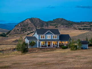 Experience serene country living in this stunning blue home nestled against rolling hills.