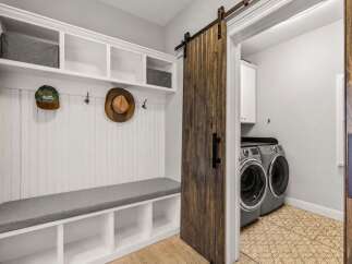 This charming mudroom features a built-in bench with ample storage cubbies and a convenient coat rack.