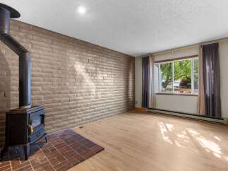 Cozy living room featuring a striking brick accent wall and a black wood-burning stove, perfect for creating a warm and inviting atmosphere.