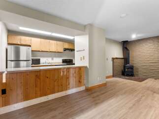 Discover a cozy living space featuring a functional kitchen with ample cabinet storage and a breakfast bar.