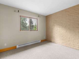 This room features a large window offering views of lush greenery and mature trees, perfect for natural light.