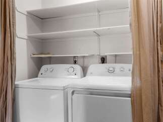 This laundry area features a white Kenmore washing machine and a white GE dryer, perfect for handling your household chores.