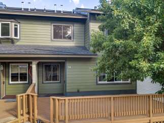 Charming townhome featuring a welcoming front porch with a wooden deck and railings.