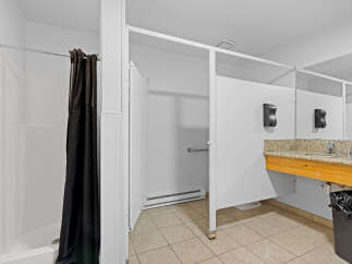 This spacious bathroom features a private shower stall with a dark curtain for privacy.