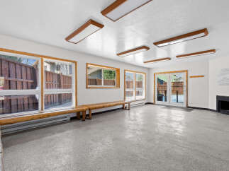 Step into this versatile space, perfect for a community room or gathering area, featuring ample natural light from large windows and a convenient access door leading outdoors.
