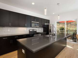 Experience modern living in this stunning kitchen featuring sleek, dark cabinetry and a spacious island with a contemporary faucet.