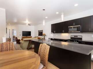 Experience modern living in this open-concept home featuring a sleek, dark-cabinet kitchen with a spacious island and stainless steel appliances.