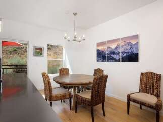 Enjoy meals with a view in this charming dining area, featuring a round wooden table and four woven chairs.