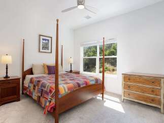 Experience comfort and style in this inviting bedroom, featuring a charming four-poster bed adorned with a vibrant, patchwork quilt.