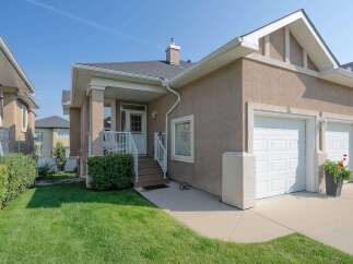 This charming townhouse features a welcoming front porch with white railings and a cozy seating area, perfect for enjoying the outdoors.