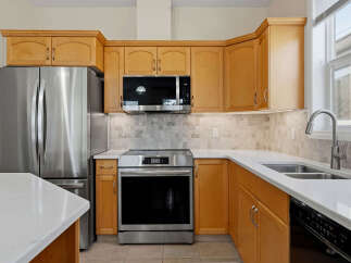 This spacious kitchen features sleek stainless steel appliances, including a French door refrigerator and a modern range with a digital display.