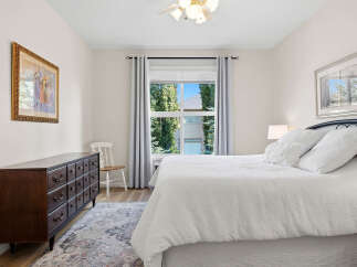 This charming bedroom features a spacious dresser and a comfortable bed adorned with plush white linens.