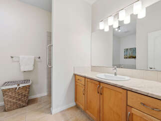 This bathroom features a spacious vanity with a light wood cabinet, a large mirror with modern lighting, and a clean white sink.