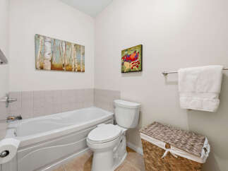 This bright and airy bathroom features a spacious bathtub perfect for relaxing soaks, complemented by a modern toilet and a convenient toilet paper holder.