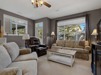 Step into this inviting living room, featuring a plush brown leather recliner and a comfortable floral-patterned sofa, perfect for relaxation.