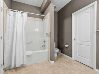 This bathroom features a pristine white bathtub and shower combination, complete with a convenient grab bar and a plush white towel.