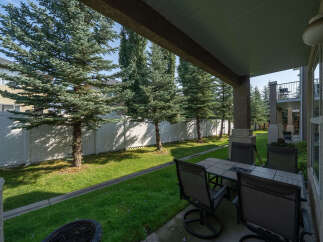 Enjoy outdoor living on this covered patio, perfect for al fresco dining or relaxing with a view of the lush green lawn and mature trees.