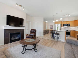 Experience modern living in this open-concept space featuring a cozy fireplace and a sleek entertainment center.