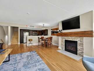 Experience modern living in this open-concept space featuring a sleek kitchen with dark cabinetry and stainless steel appliances, flowing seamlessly into a dining area perfect for entertaining.