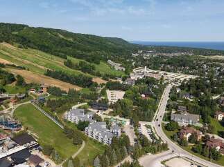 Discover this stunning aerial view showcasing a vibrant community nestled against a lush green hillside, perfect for outdoor enthusiasts.