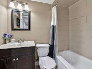 This bathroom features a modern vanity with a sleek faucet and a spacious sink, complemented by a large framed mirror above.