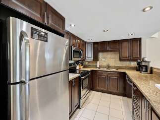 Experience culinary convenience in this beautifully appointed kitchen, featuring sleek stainless steel appliances including a refrigerator and microwave.