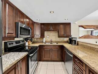 This U-shaped kitchen boasts rich, dark wood cabinetry complemented by elegant granite countertops and a classic subway tile backsplash.