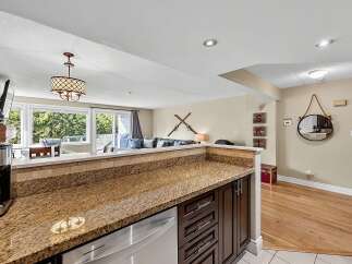 Experience comfortable living in this inviting space, featuring a well-appointed kitchen with granite countertops and dark wood cabinetry.