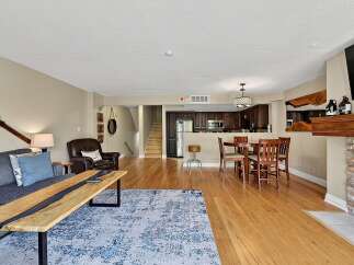Experience modern living in this open-concept condo featuring a stylish living area with a unique live-edge coffee table and a cozy leather armchair.