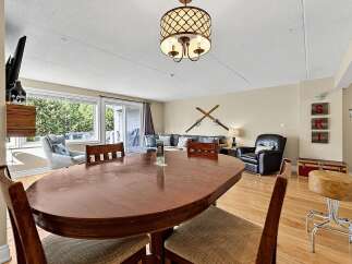 This inviting living and dining area features a spacious wooden dining table perfect for family meals, complemented by a comfortable seating area with plush sofas and armchairs.