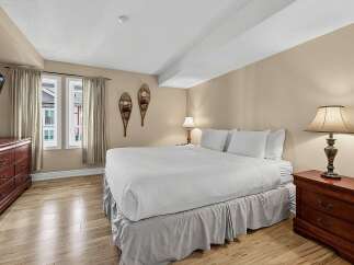 Experience cozy comfort in this inviting bedroom, featuring a plush king-sized bed adorned with crisp white linens.