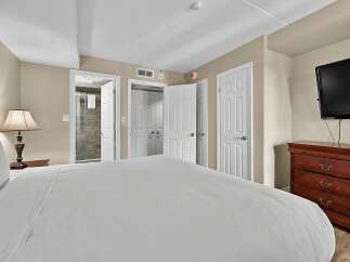 Experience comfort and convenience in this well-appointed bedroom, featuring a plush bed, a bedside lamp, and a spacious dresser.