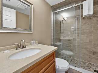 Experience modern comfort in this beautifully appointed bathroom, featuring a sleek glass-enclosed shower with elegant tilework and a pebble-stone floor.